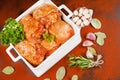 Chicken thighs marinated in red sauce in a roasting dish with rosemary leaves and various spices. Raw chicken meat. Royalty Free Stock Photo