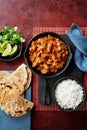 Chicken tikka masala spicy curry meat food Butter chicken, rice and naan bread on red vine dark background. Traditional Indian Royalty Free Stock Photo