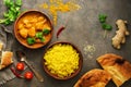 Chicken tikka masala with yellow rice and naan on a dark brown background. Indian food. Top view, copy space, flat lay