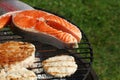 Chicken or turkey burgers and salmon fish on grill Royalty Free Stock Photo