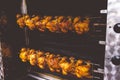 Chicken on the turning spit with tasty golden-yellow roasted skin in 2 rows