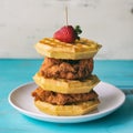 Chicken and waffles stacked high on a white plate. Strawberry garnish. Close up side view. Royalty Free Stock Photo