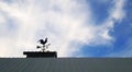 Chicken windmill on roof with blue sky and cloud background with copy space. Object for tell wind direction and force.