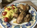 Chicken wings with couscous tomatoes and spices on a plate.