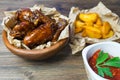 Chicken wings in a fragrant and pungent sauce with sesame seeds. A glass of fresh cold beer and fried potatoes with rustic tomato Royalty Free Stock Photo