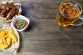 Chicken wings in a fragrant and pungent sauce with sesame seeds. A glass of fresh cold beer and fried potatoes with rustic tomato Royalty Free Stock Photo