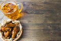 Chicken wings in a fragrant and pungent sauce with sesame seeds. A glass of fresh cold beer and fried potatoes with rustic tomato Royalty Free Stock Photo