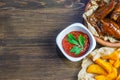 Chicken wings in a fragrant and pungent sauce with sesame seeds. A glass of fresh cold beer and fried potatoes with rustic tomato Royalty Free Stock Photo