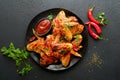 Chicken wings. Grilled or baked chicken wings with sesame seeds and ketchup or spicy tomato sauce on black plate on black or dark Royalty Free Stock Photo