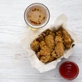 Chicken wings with sauce, cold beer over white wooden surface, top view. From above, flat lay