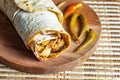 Chicken wrap doner kebap in lavash pita bread durum with thin green pepper pickle on wooden platter