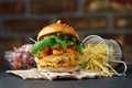 Chickenburger on the wooden plates with cheese, bacon, tomatos, green and red salad and french fries