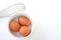 Chickken eggs in a bowl and egg whisks on white background. Royalty Free Stock Photo