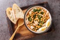 Chickpea stew with spinach and cod or potaje de vigilia close-up in a bowl on the wooden tray. Horizontal top view