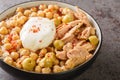 Chickpeas in broth served with canned tuna, olives and poached egg close-up in a bowl. Horizontal