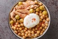 Chickpeas in broth served with canned tuna, olives and poached egg close-up in a bowl. Horizontal top view