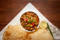 Chickpeas masala Spicy chola or chhole curry and Bhatura or Puri garnished with fresh green coriander and ingredients.