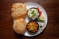 Chickpeas masala Spicy chola or chhole curry and Bhatura or Puri garnished with fresh green coriander and ingredients.