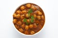 Chickpeas masala Spicy chola or chhole curry garnished with fresh green coriander and ingredients. Served in a ceramic bowl.