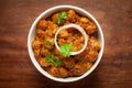 Chickpeas masala Spicy chola or chhole curry garnished with fresh green coriander and ingredients. Served in a ceramic bowl.