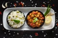 Chickpeas masala Spicy chola or chhole curry and Pulav Rice garnished with fresh green coriander and ingredients. Served in a