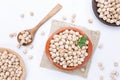 Chickpeas on plates and wooden spoon on white background. Top view