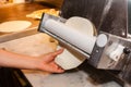 Chief cook rolls the dough for pizza with special equipment Royalty Free Stock Photo