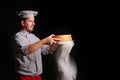 Chief cook is sifting flour through a sieve on black background Royalty Free Stock Photo
