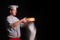 Chief cook is sifting flour through a sieve on black background Royalty Free Stock Photo