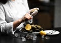 Chief cook woman hands open oysters with knife with lemon and ice in restaurant table