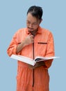 The chief mechanic in an orange uniform holding big book. Stand and read the maintenance manual carefully. Portrait with studio