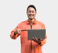 The chief mechanic in an orange uniform holding laptop computer. Standing with his finger thumbs up. Portrait with studio light