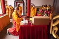 The Chief Monks wearing a red robe and an orange suit while leading the praying process