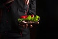 Chief sprinkles salt on a sliced steak with beef and vegetables in a plate. The concept of serving dishes to order