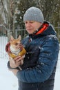 Chihuahua dog in a fashionable jacket in the arms of the owner in winter on a walk, winter time, snowfall
