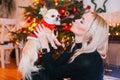 Chihuahua dog wearing in the costume of Santa Claus with blond woman sit under christmas tree Royalty Free Stock Photo
