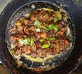 CHIKEN FRI WITH GREEN CHILLI IN A BLACK PAN WITH CORIANDER LEAVES