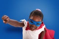 Child acts like a superhero to save the world on blue background Royalty Free Stock Photo