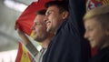 Child and adult Spanish football fans waving flag, singing national anthem