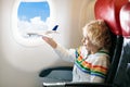 Child in airplane. Kid in air plane sitting in window seat. Flight entertainment for kids. Traveling with young children. Kids fly