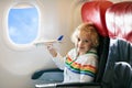 Child in airplane. Kid in air plane sitting in window seat. Flight entertainment for kids. Traveling with young children. Kids fly