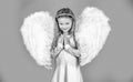 Child with angelic face. Cute child girl posing with angel wings. Beautiful little angel girl standing with your arms