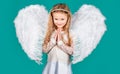 Child with angelic face. Cute child girl posing with angel wings. Beautiful little angel girl standing with your arms