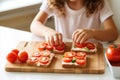 child arranging tomato slices on whole grain bread