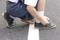 Child Asian tying shoes on the roadside