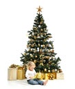 Child baby girl kid sitting under decorated gold Christmas tree with gold patchwork gift Royalty Free Stock Photo