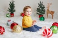 Child baby in yellow sweater clothes sitting on white fluffy rug celebrating Christmas or New Year Royalty Free Stock Photo