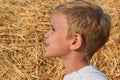 A child on the background of straw, holding a spikelet in his teeth and smiling. Emotions, warmth