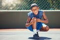 Child with a band aid on a knee injury from sports outside on a basketball court touching his bandage. Boy with a Royalty Free Stock Photo