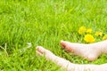 Child bare feet resting on a sunny green meadow with bright yell